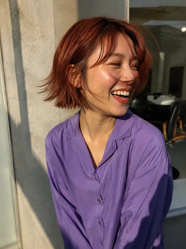 Laughing client with a softly layered copper bob